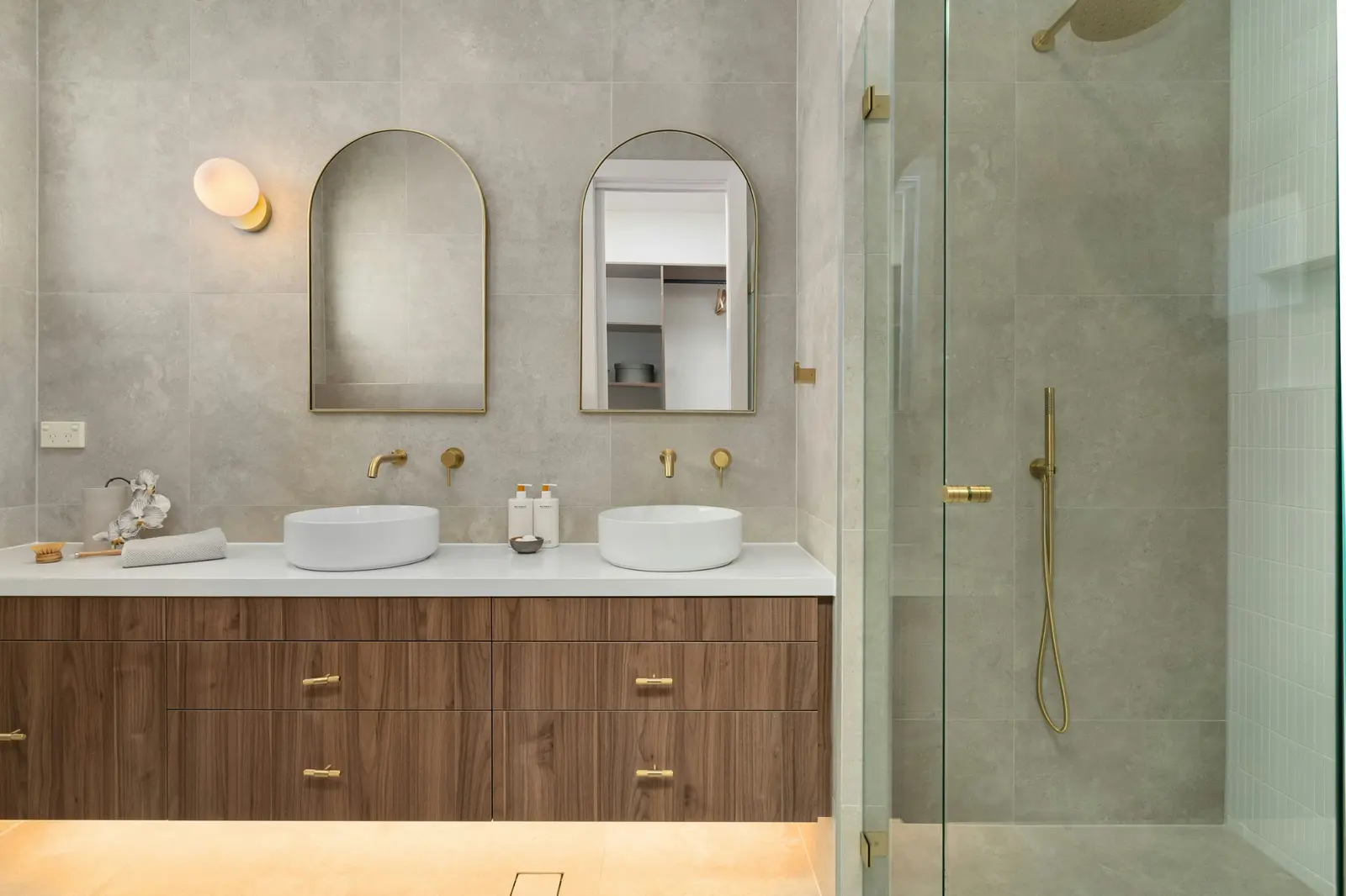 Contemporary bathroom with arched mirrors, twin basins and brushed brass tapware