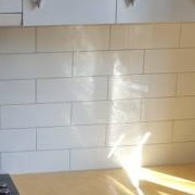 Close-up of white subway tiles meeting the benchtop below the wall cabinets