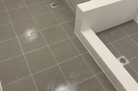 Grey floor tiles meeting a white tiled bath hob, before fit-off