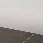 Close-up of white marble-look wall tiles meeting dark floor tiles in a straight line